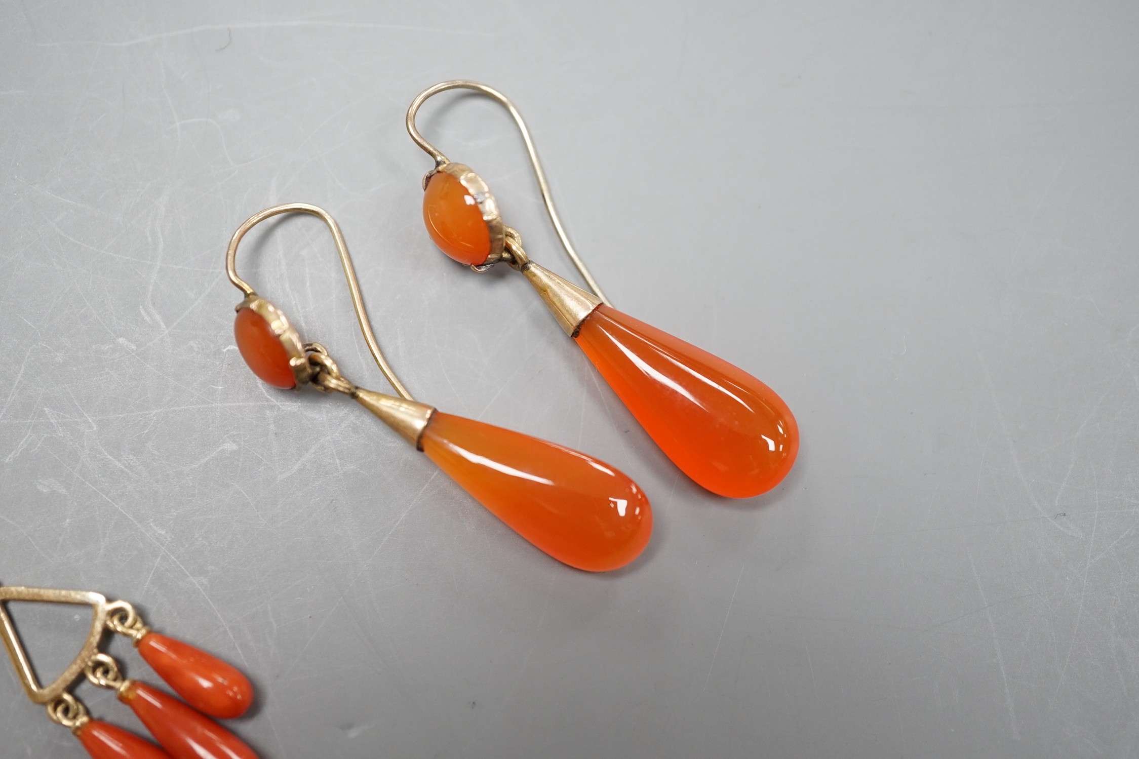 A pair of yellow metal and triple drop coral earrings, overall 37mm, gross 4.4 grams and a pair of carnelian set drop earrings.